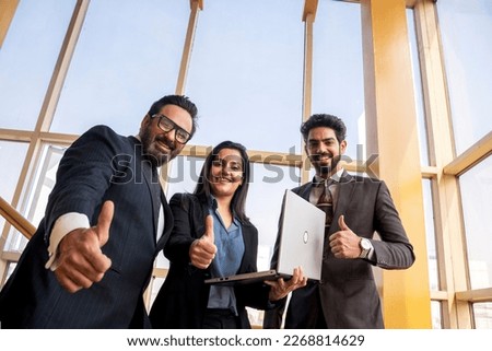 Indian businesspeople showing thumps up at office.
