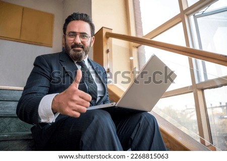 Indian businessman using laptop and showing thumps up