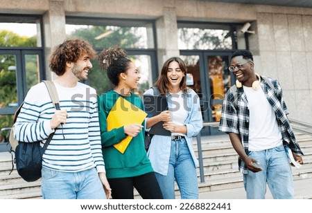 Happy international university friends walking together in campus, chatting and laughing outdoors after school