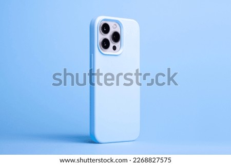 iPhone 14 and 13 Pro Max in light blue case back side view isolated on blue background, phone cover mock up in monochrome colours