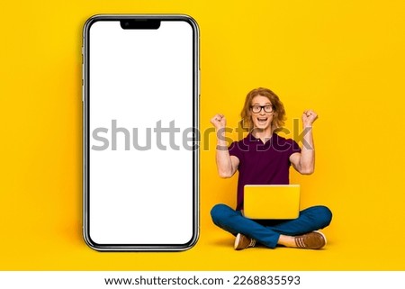 Full body photo of delighted successful man sit floor raise fists celebrate isolated on yellow color background