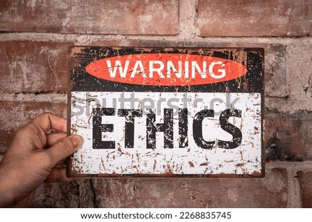 Ethics Concept. Warning sign with text in hand of woman. Red brick background.