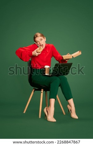 Multi tasks. Young woman, employee working and eating, talking on phone, posing over green studio background. Busy worker. Concept of business, emotions, official fashion, lifestyle Royalty-Free Stock Photo #2268847867