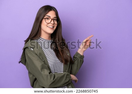 Young Brazilian woman isolated on purple background pointing finger to the side