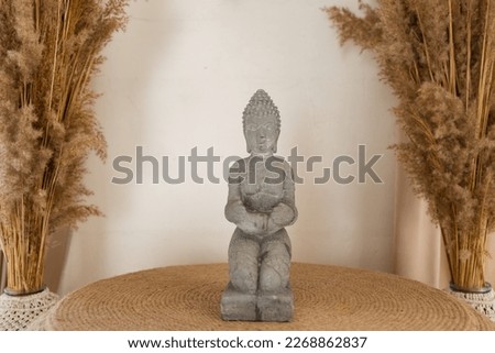 Modern minimal interior and Buddha statue near window. Home decor with natural materials in bright living room interior at bohemian style. Calmness and mental health concept