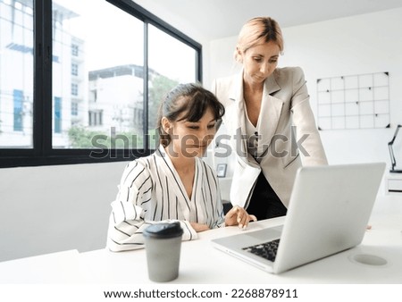 Businesswoman working with woman colleague planning corporate business strategy in office. Female businessperson group meeting, talking, brainstorming in marketing projects idea together as teamwork