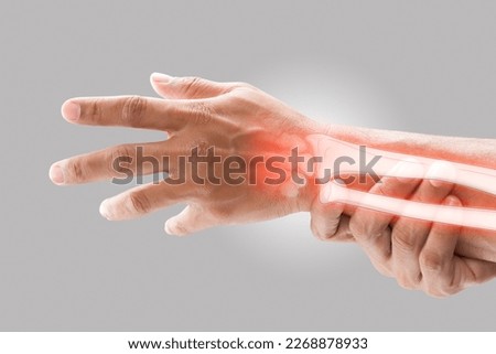 A man massaging painful wrist on a gray background. Pain concept. Osteoporosis Royalty-Free Stock Photo #2268878933
