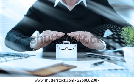 Insurer protecting a briefcase with his hands; light effect Royalty-Free Stock Photo #2268882387