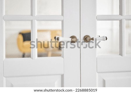 Old-style door, white - handle close up. The interior of a bright living room in a modern apartment.
