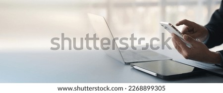 Business man looking at financial information from a mobile phone, he is checking company financial documents, he is an executive of a startup company. Concept of financial management. Royalty-Free Stock Photo #2268899305