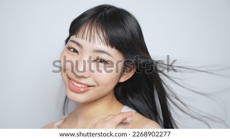 Young Asian girl with long black hair blowing in the wind.