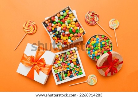 Set of different sweet candy in a paper box with a satin ribbon on a colored background. Holiday concept. Royalty-Free Stock Photo #2268914283