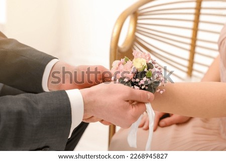 Young man tying corsage around his prom date's wrist, closeup Royalty-Free Stock Photo #2268945827