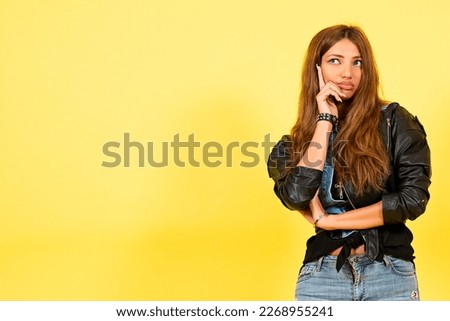 Yellow background, a girl in a leather jacket in the style of rock, shows emotions, free space for text, thinks