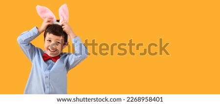 Cute little boy with bunny ears on yellow background with space for text