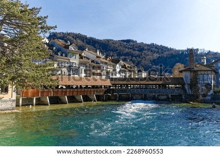 Scenic view over City of Thun with Aare River and covered wooden bridge on a sunny winter day. Photo taken February 21st, 2023, Thun, Switzerland.