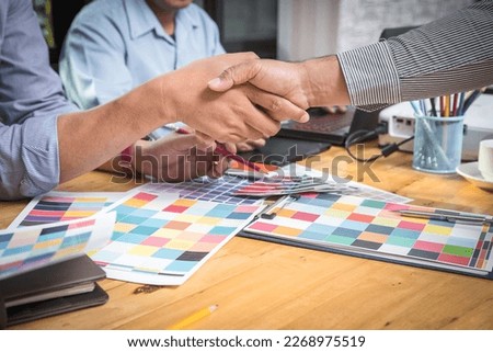 Businessmen shaking Hands after Meeting. Interior designer discussion and chooses a color chart for home design. Graphic designers working on color patterns at modern office.