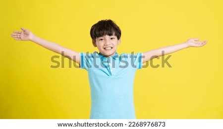 portrait of an asian boy posing on a yellow background Royalty-Free Stock Photo #2268976873