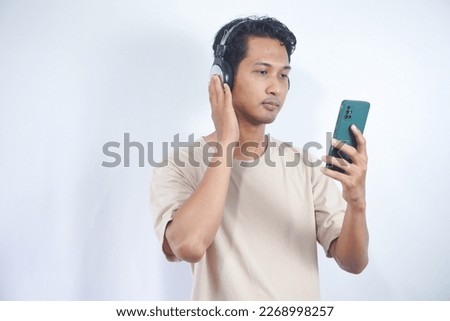 Asian man listening to music mobile phone app wearing headphones. smile and enjoying the music, isolated on white background