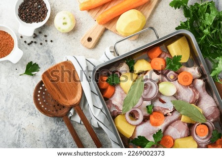 Cooking chicken bouillon or roast in cooking pan or pot with vegetables potatoes, carrots and herbs on kitchen grey concrete worktop scenery from above.  Cooking preparing chicken stock. Mock up.