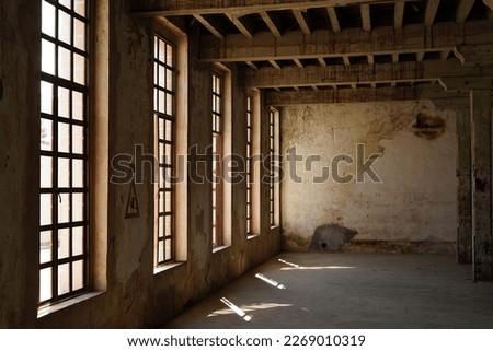 antigua fabrica de textiles, con ventanales enormes y vigas de madera, muro con manchas de agua