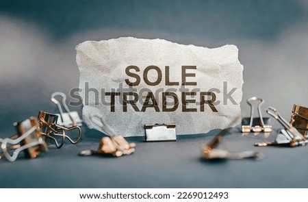 SOLE TRADER, text on torn paper on gray background