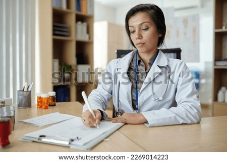 Serious general practitioner filling medical documents