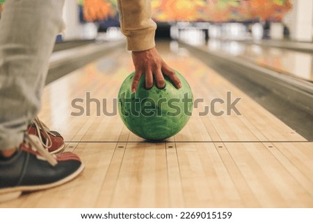 Man's hand holding a green bowling ball ready to throw it