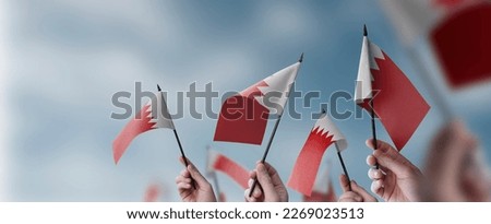 A group of people holding small flags of the Bahrain in their hands. Royalty-Free Stock Photo #2269023513