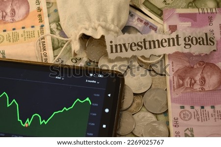 A Selective focus picture of a Investment goals word with currency notes, Stock market graph and coins in the background, Investment themes Royalty-Free Stock Photo #2269025767