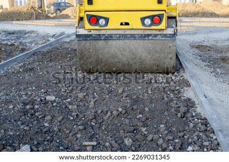 A new footpath is under construction as builders bring stone, levelling it and compacting Royalty-Free Stock Photo #2269031345