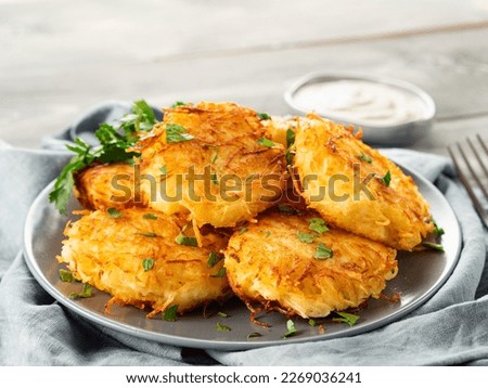 Close up view of potato pancakes. Potatoes pancakes latkes, flapjacks, hash brown or potato vada on gray plate over gray wooden table, with fresh parsley and sour cream. Copy space for text. Royalty-Free Stock Photo #2269036241