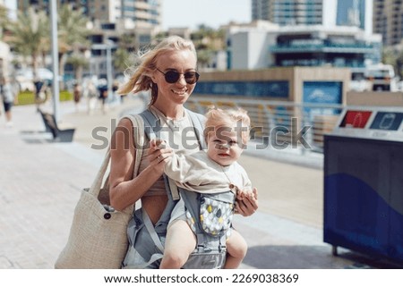 Happy woman with little daughter walking on the street.