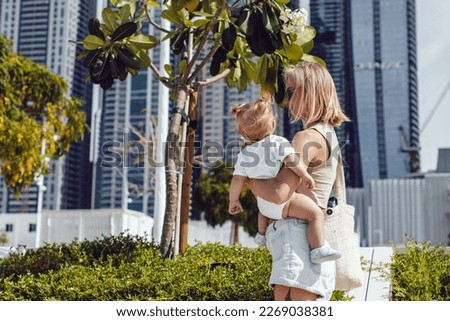 A woman with a child in her arms walks around the city. Mom and daughter.