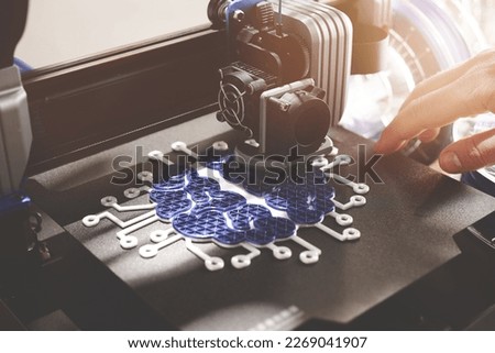Person working on black 3d printer making brain sculpture in warm light. filament rolls and hand in background. selective focus on print head and part of print object. Modern production concept