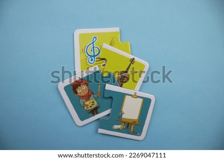 Jigsaw puzzle pieces with violin, artist and painting canvas picture placed on blue background.