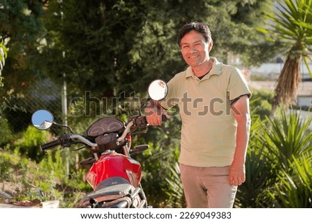 Happy Hispanic adult man with his new motorcycle - Latino man buying a motorcycle - Older man with his motorcycle outside his house