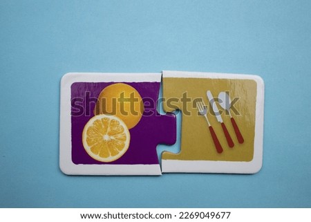 Puzzle pieces with oranges and kitchen utensils picture placed side by side on a blue background.