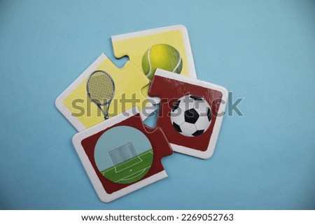 Picture puzzle pieces with volleyball ball, racket, soccer ball and soccer goal placed on blue background.