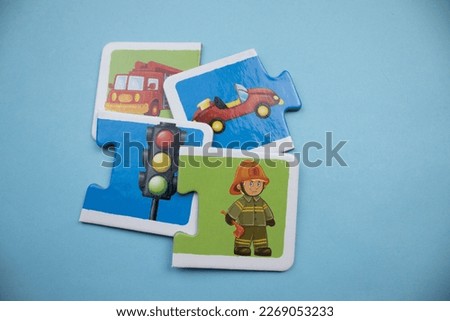 Colorful puzzle pieces with fire engine, car, traffic signs and firefighter picture placed on blue background.