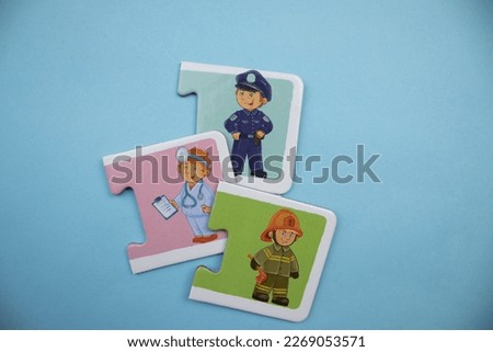 Puzzle pieces with pictures of police, doctor and firefighter placed on blue background.