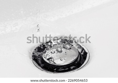 Drops of clean water on the sink drain valve. Selective focus.
