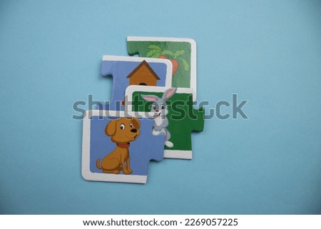 Puzzle pieces with carrot, hut, rabbit and dog picture placed on blue background.