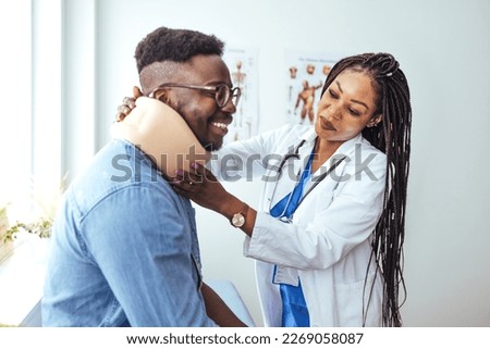 Young man with injury of neck visiting doctor in clinic. Doctor examining a patient at desk in medical office. Doctor talking to a male patient with cervical collar at the hospital
