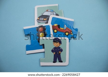 Puzzle pieces with police car, car, traffic sign and police picture placed on blue background.