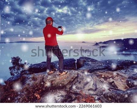 Hiker taking vacation photos of beautiful sunset in autumn nature  by smartphone, holiday or vacation travel 