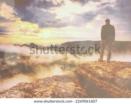Landscape photograper with camera ready in hand. Man climbed up on exposed rock for fall photos 