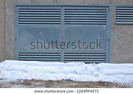 cast concrete formwork garage. grilles and garage doors are made of galvanized sheet metal. the industrial gray color dominates. durable solution. snow on the roof and in front of the entrance