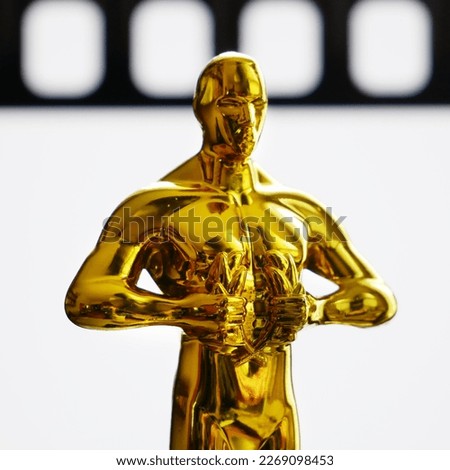 Hollywood Golden Oscar Academy award statue on film background. Success and victory concept.