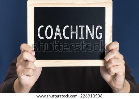 Man holding blackboard with word coaching